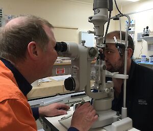 Andy gazes into Matt’s eyes through the slit lamp during the Lay Surgical Assistant training.