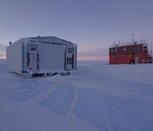 The white work shop building and the foreground with the red operations building in the background both parked up on the blue ice.