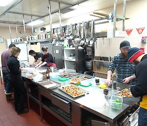 People working around the kitchen bench with the mid-winter food preparation.