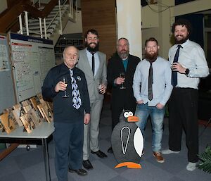 Four station plumbers standing with Jacob and a timber penguin.