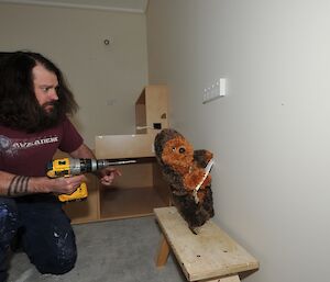 Station electrician pretending to sneak up on Walter (stuffed soft toy) as if to drill a hole in him.