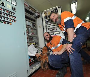 Two station electricians with Walter (stuffed soft toy) looking in a switchboard cabinet in the main power house.