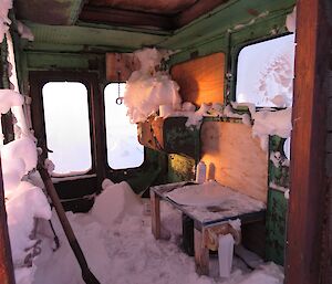 Looking inside the old dozer cabin that has been converted into the toilet cubical at Jack’s hut which has the floor and sections of the toilet seat and walls covered snow.