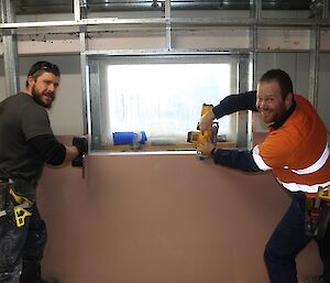 Expeditioner having fun pretending to cut a metal wall frame section with a battery operated wood saw.