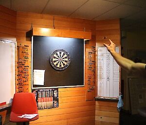 Murray throwing a dart at the laminated dart board with the dart in mid-flight.