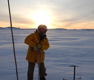 Jeff drilling a hole through the ice with a battery drill in the special ice drill bit