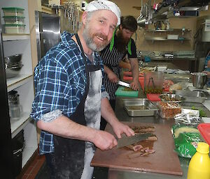 Cameron slicing meat with a large carving knife.