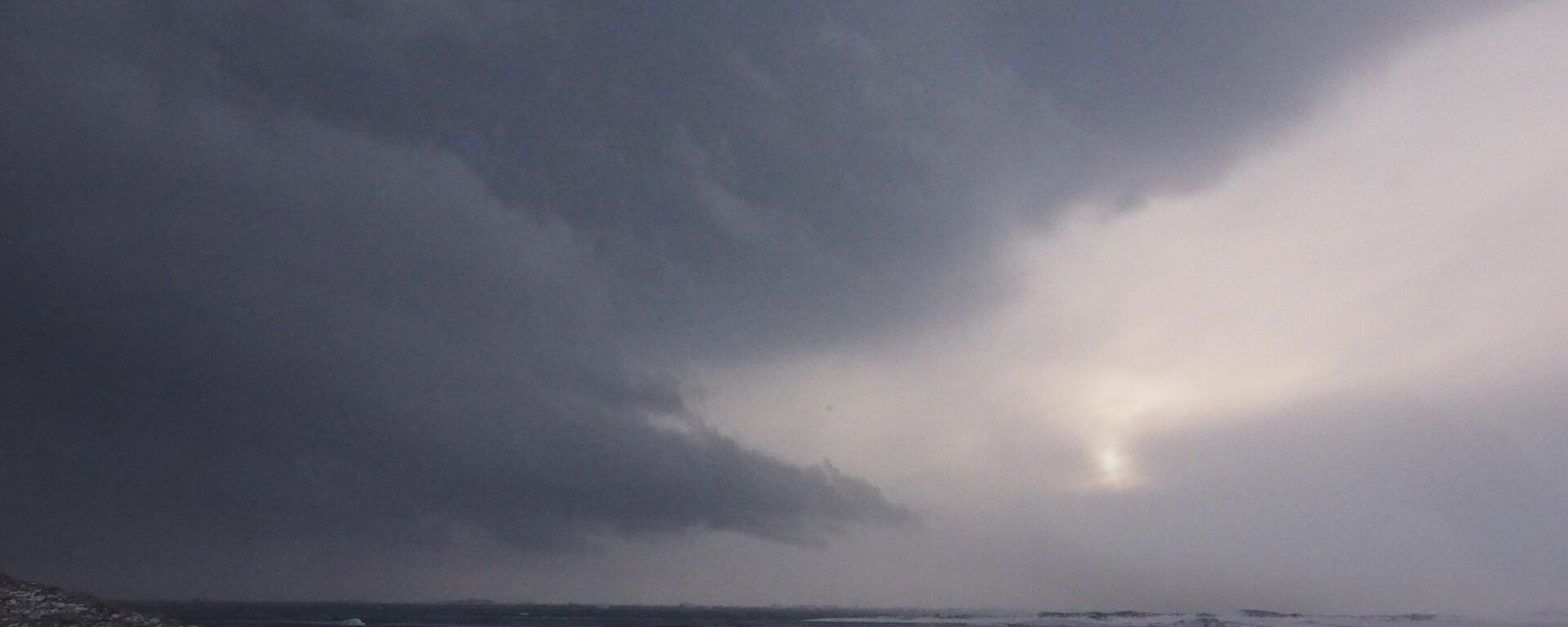 Looking out over the open water that was sea ice with a large dark storm cloud filling the sky.