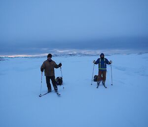 Two expeditioners on skis with each of one towing a small sled containing their survival gear.