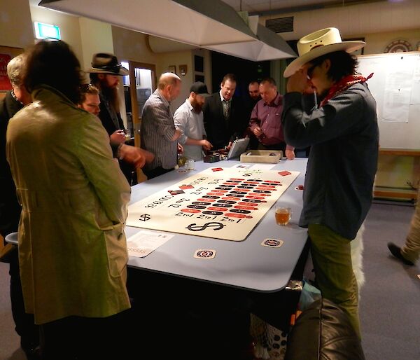 Roulette players standing around the makeshift roulette table.