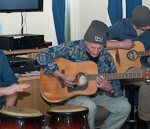 Tom playing the bongo drums with Jeff and Murray playing guitars.