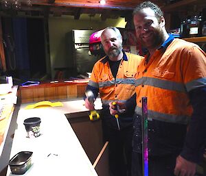Dean and Cam standing behind the newly refurbished bar, Cam with a battery drill in hand and Dean with a screw driver.