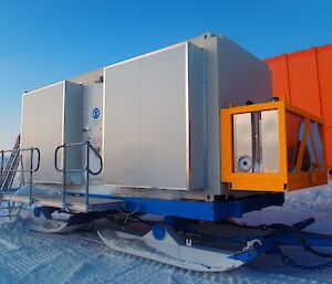 The white generator van mounted on a blue sled.