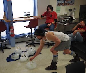 An athlete sliding a curling stone made of ice across the floor.