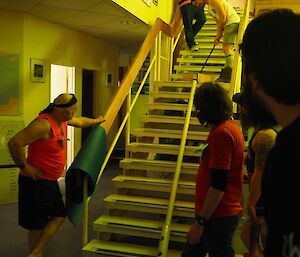 An athlete hitting the golf ball into some PVC pipe that runs down the stairs surrounded by some eager onlookers.
