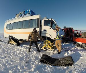 The bus broken down due to a missing front track which is laying in the foreground.