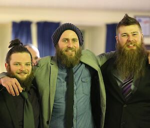 There expeditioners getting a mechanical team photo while dressed up for the end of winter dinner.