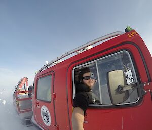 Expeditioner riding in the red Hagglund taking a photo as driving along.