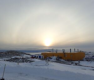 Sun setting over the science building with a halo around the sun.