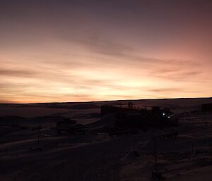 The sun coming up over the main power house late in the day with multiple colours in the thin cloud cover.