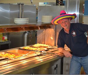 Andy standing in front of his Mexican food in the bain-marie wearing a brightly coloured sombrero
