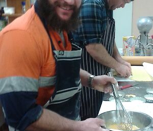 AJ smiling as he beats son eggs. Dean in the background cutting pastry.