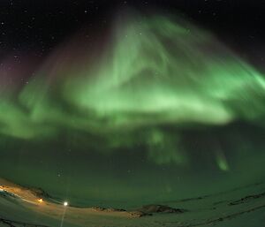 A beautiful wide angle shot of a bright green aurora covering the whole night sky.