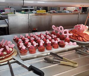 Pink cupcakes, pink sponge and pink pikelets each with a pink ribbon out of meringue ready for morning tea.