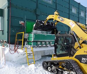 Tipping snow into the snow melter with the Wilkins skid steer loader.