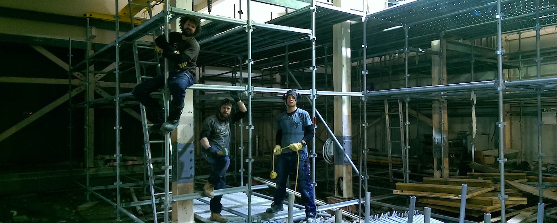 Three expeditioners position for a photo on the scaffold that they are pulling down.