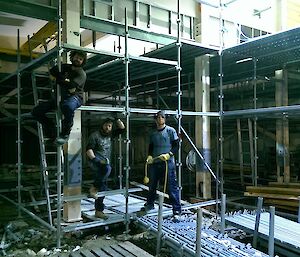 Three expeditioners position for a photo on the scaffold that they are pulling down.