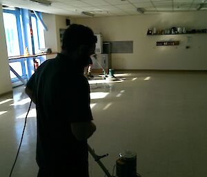 Two expeditioners working on the mess floor with the rotary floor polishers.