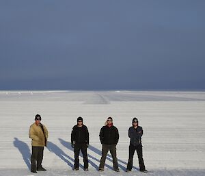 Four expeditioners standing in a line with the runway in the background