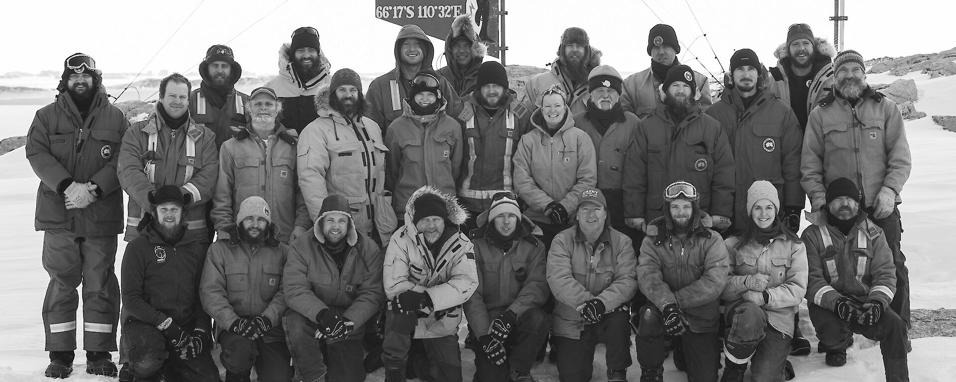 The 27 expeditioners in three rows in front of the Casey sign for the winter team black and white photo.