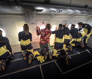 Several expeditioners looking out of place windows on approach to Antartica