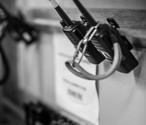 Two hand held portable radios hanging on a rack