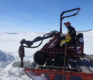 An expeditioner operates a small digger on the sea ice