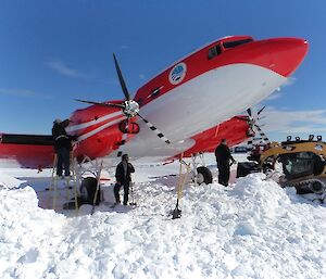 Snow is dug out from around an aircraft