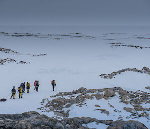 A group of expeditioners walking across the snow.