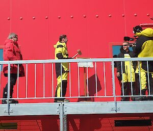 Minister Frydenberg holds a mallet in his hand in order to crack an ice sheet opening the new accommodation block at Casey.