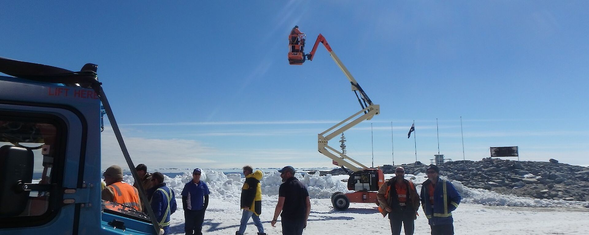 A photographer stands on a cherry picker in order to get a good shot