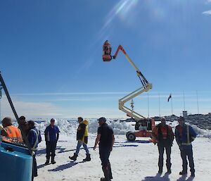 A photographer stands on a cherry picker in order to get a good shot