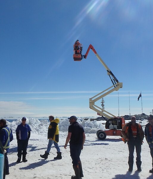 A photographer stands on a cherry picker in order to get a good shot