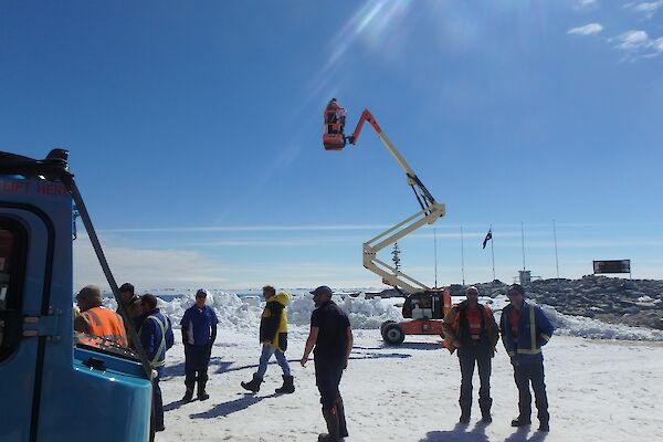 A photographer stands on a cherry picker in order to get a good shot