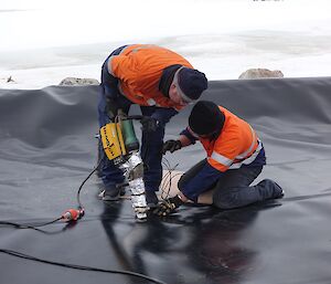 Two tradesman join the membrane under the bio piles