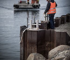 An expeditioner waits to tie up the barge at the Casey wharf during resupply