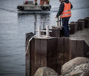 An expeditioner waits to tie up the barge at the Casey wharf during resupply