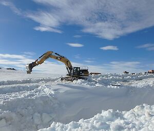 An excavator clears snow away