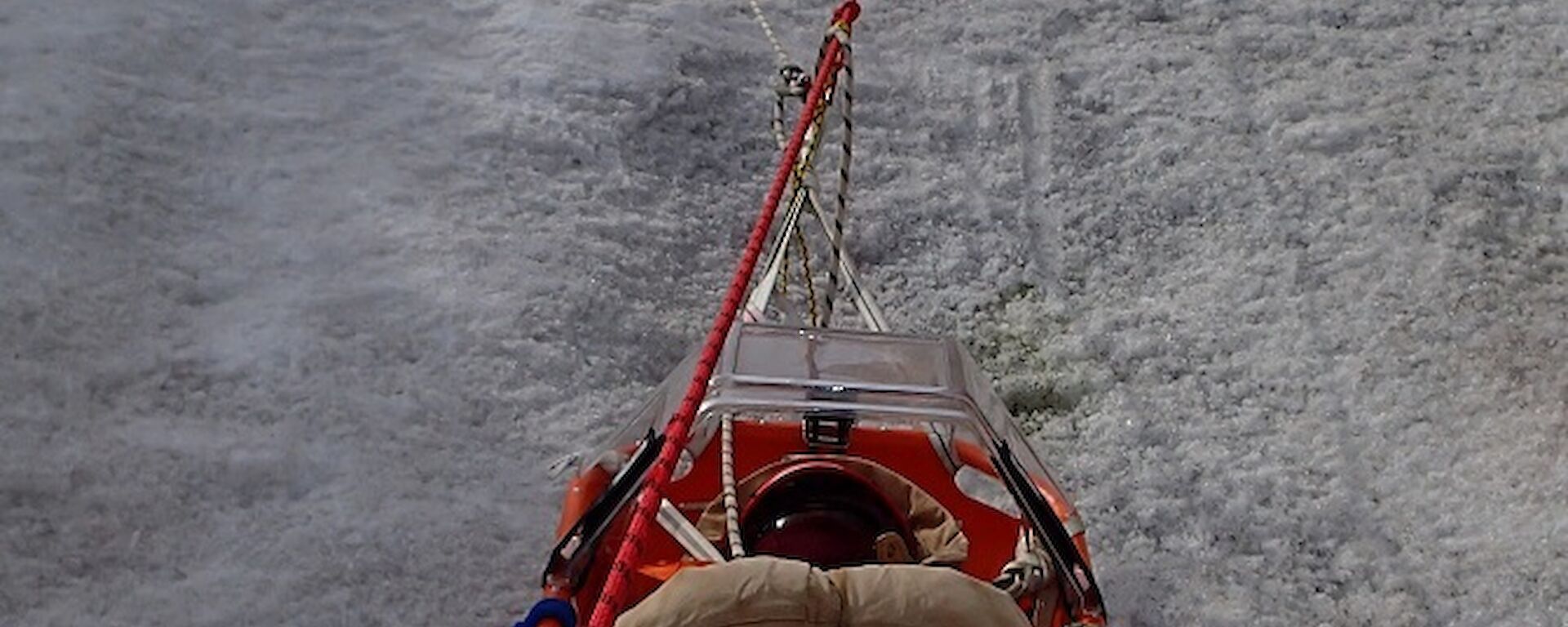 Expeditioners lower a patient down a slope as part of SAR Training