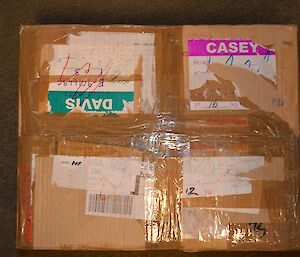 Cardboard box showing repeated use with old stickers for Green for Davis, Pink for Casey and Red for Mawson.